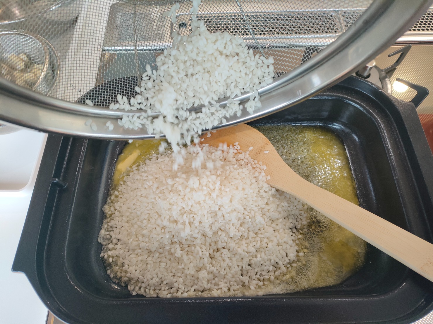 コンロにキャセロールを乗せ、バターを入れ、中火であたためる。バターがとけきったら、米を入れ、軽く透き通るまで炒める。塩、オレガノを入れ、全体に混ぜ合わせる。