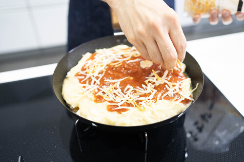 ２のホワイトソース、ミートソースをかけたら、チーズをのせる。蓋をして、チーズが溶けたら、パセリをふる。