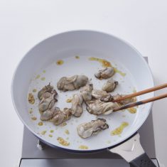 フライパンにオリーブ油をいれ中火で熱し、にんにくと牡蠣を加える。１０秒ほど炒めたら、白ワインをいれ蓋をし３０秒程蒸したら、牡蠣だけをトングで器に取り出す。