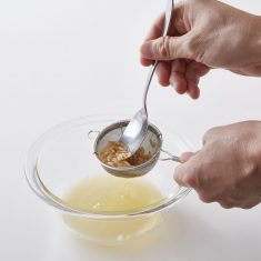 メロンの種とワタを茶こしにいれ濾し、ボウルに果汁をいれる。